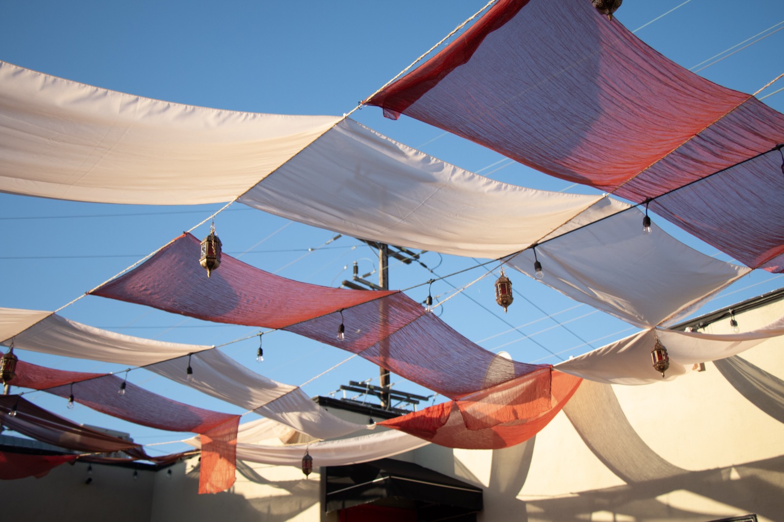 Fabric canopies and hanging lanterns strung above the bazaar against a blue sky
