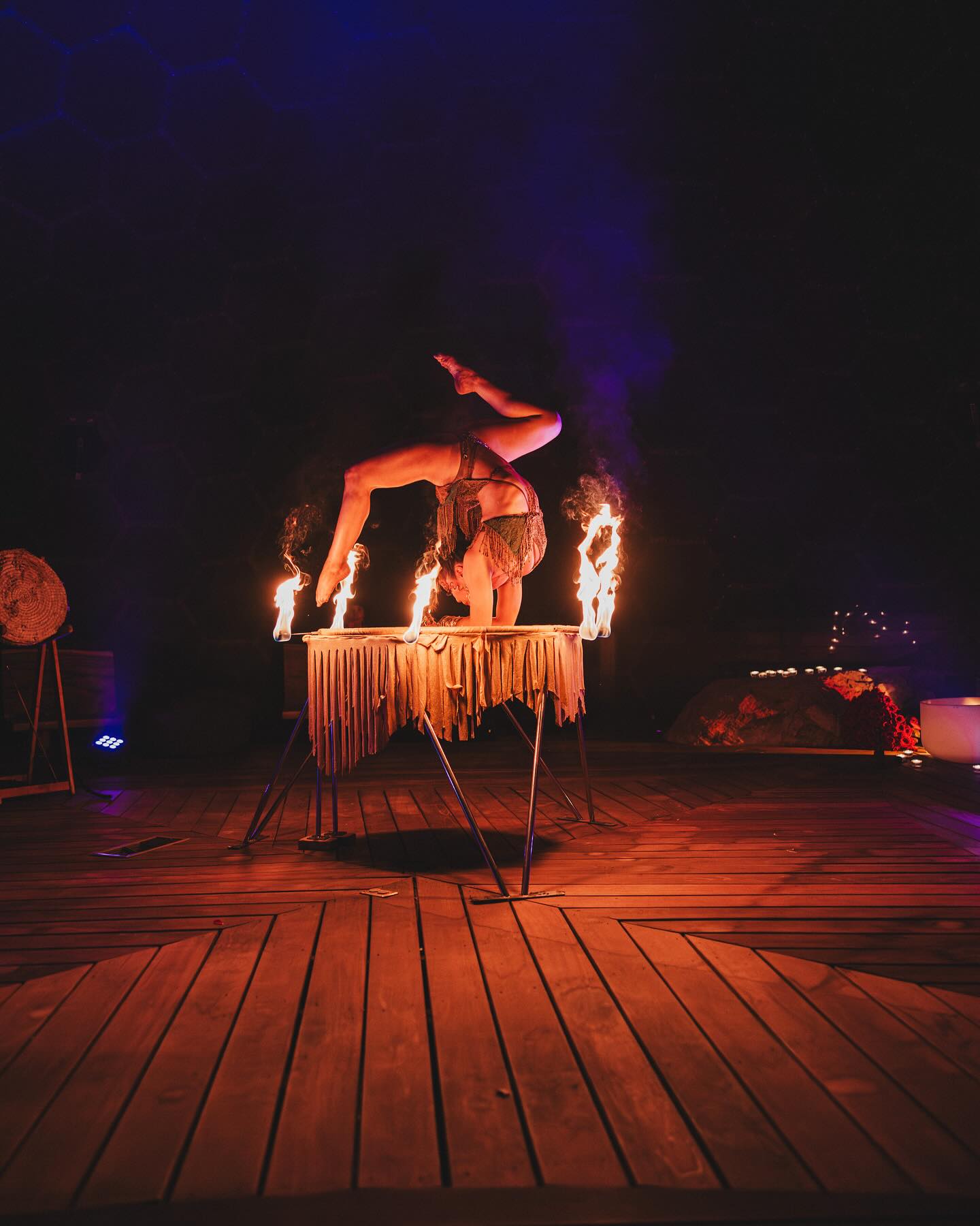 Contortionist in a handstand above a table of fire torches