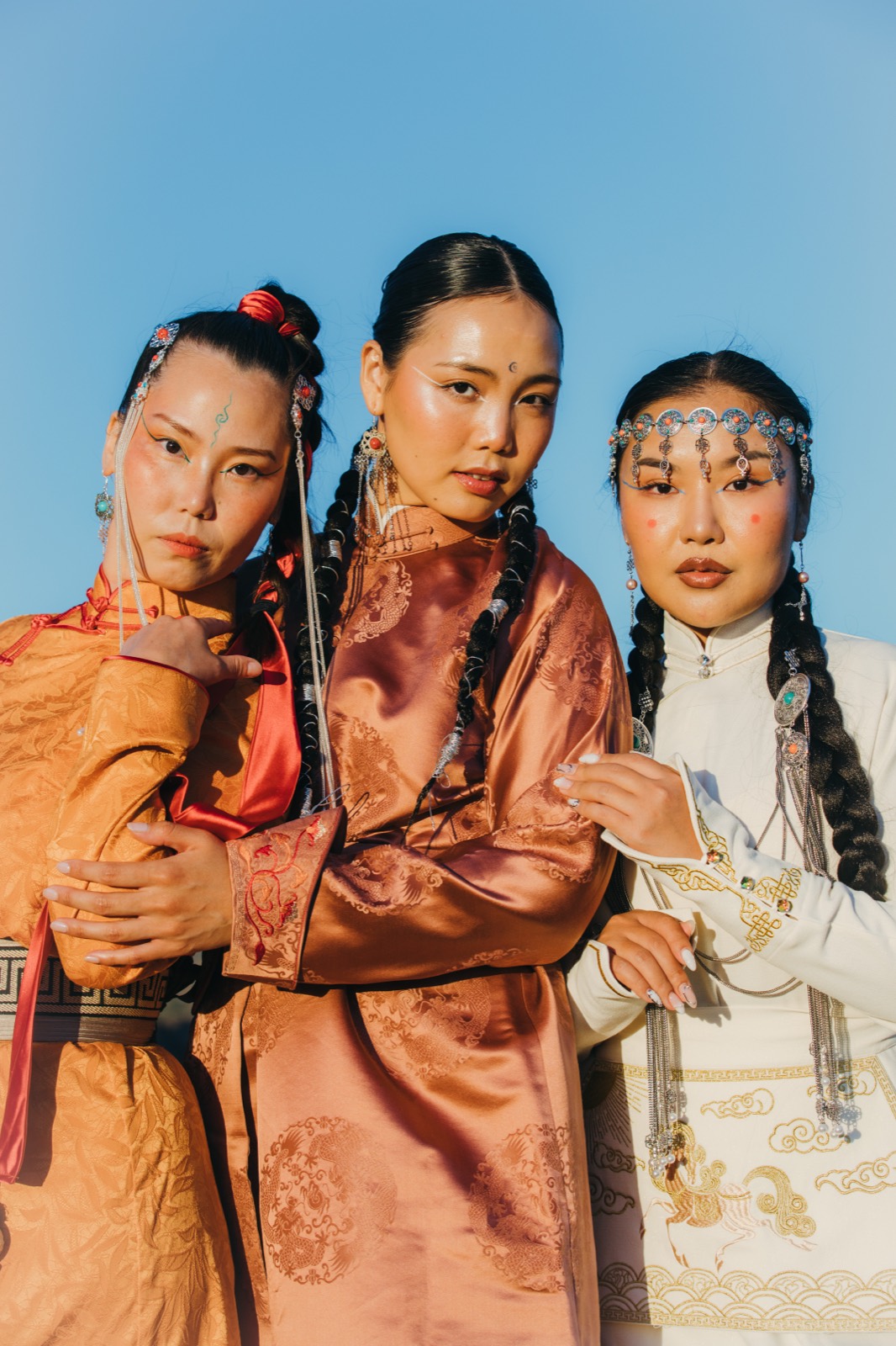 Three guests in traditional deel and silver headdresses posing together