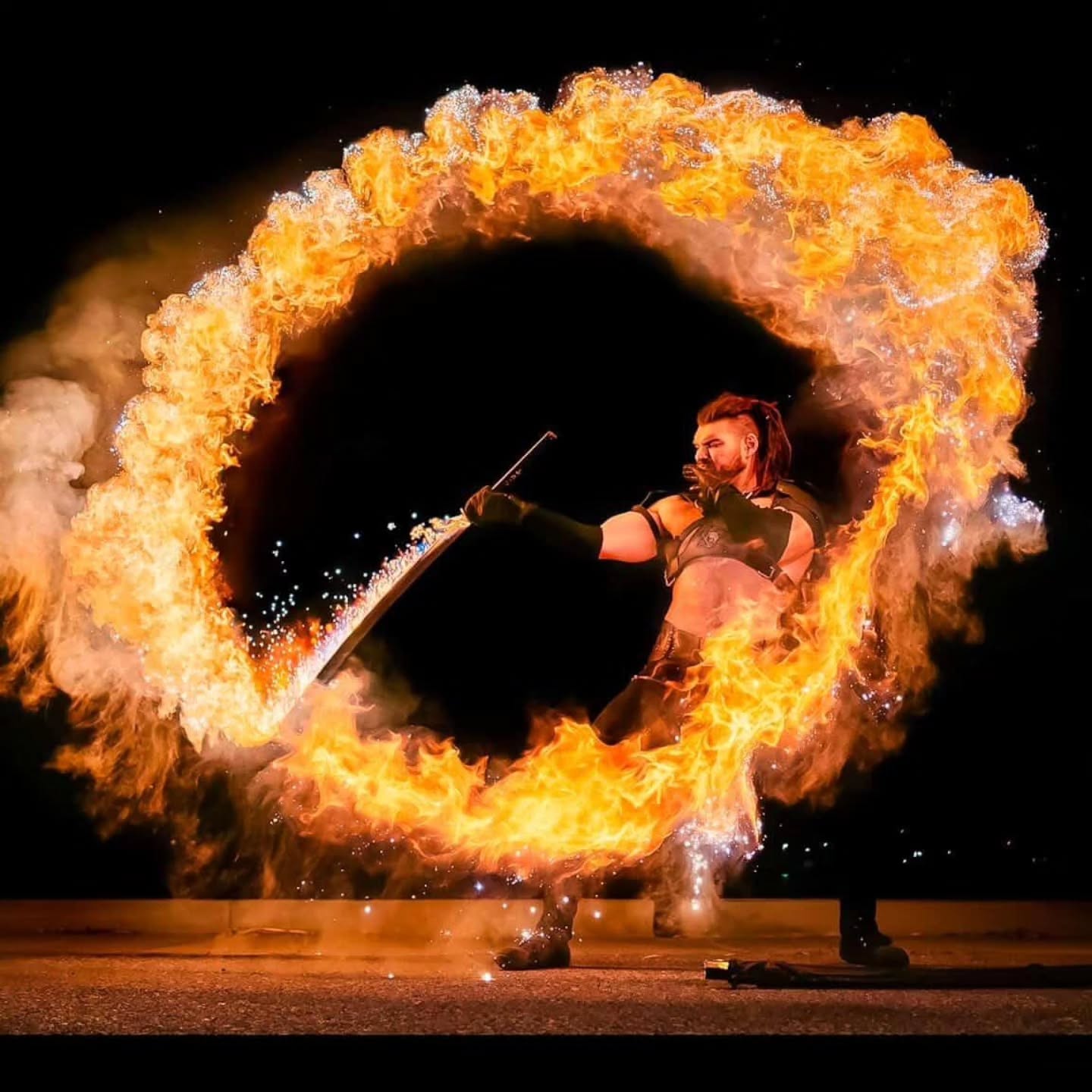 Fire performer swinging a blade through a full ring of flame