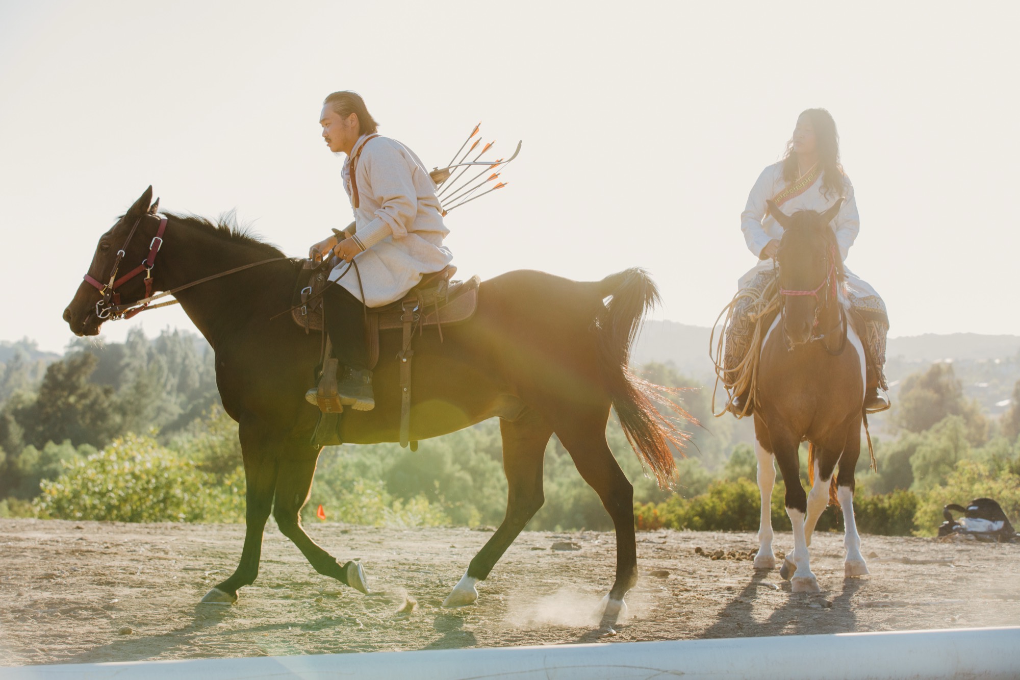 Two riders crossing open ground in low golden light